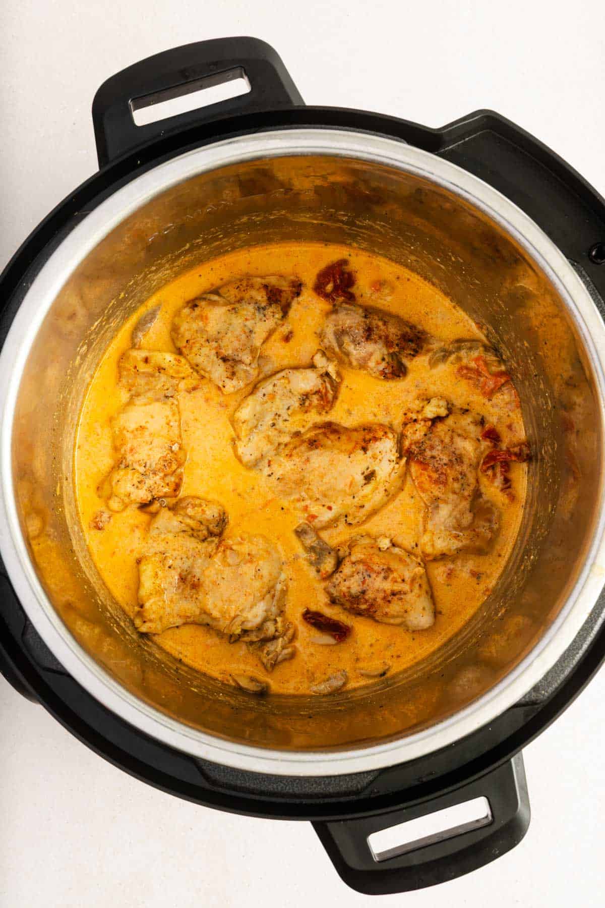 Overhead view of an Instant Pot with creamy sun-dried tomato parmesan chicken.
