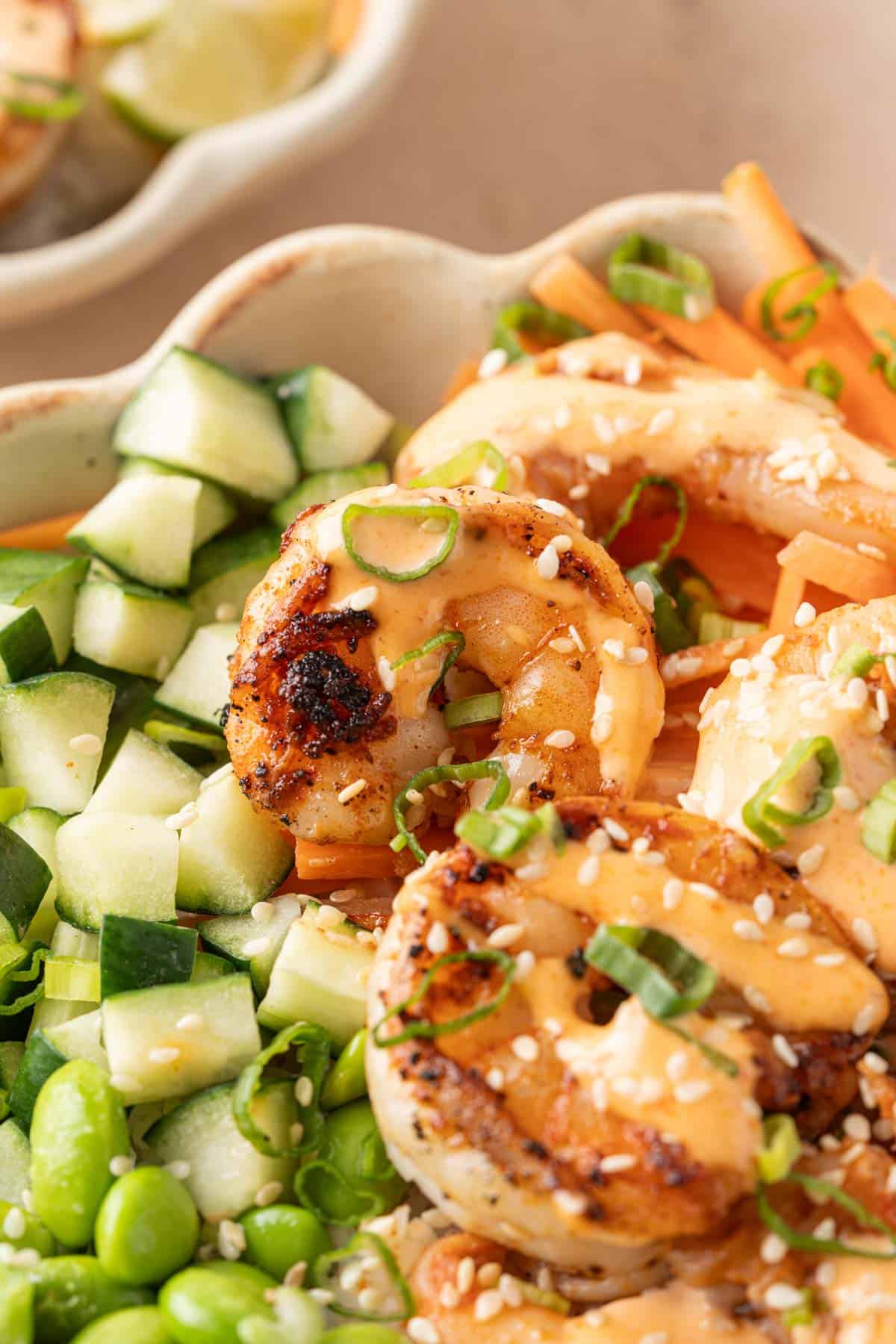 Close up view of shrimp in a rice bowl with a drizzle of spicy mayo on top.